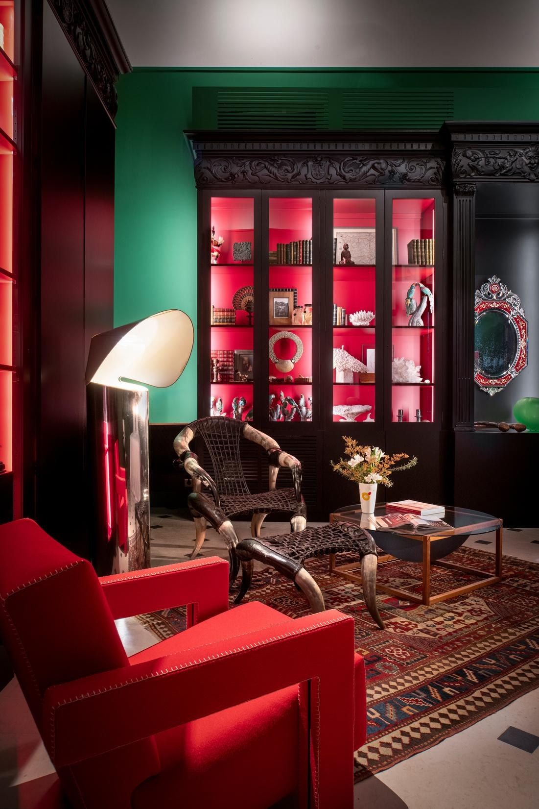 Salón biblioteca con butaca roja y paredes verdes