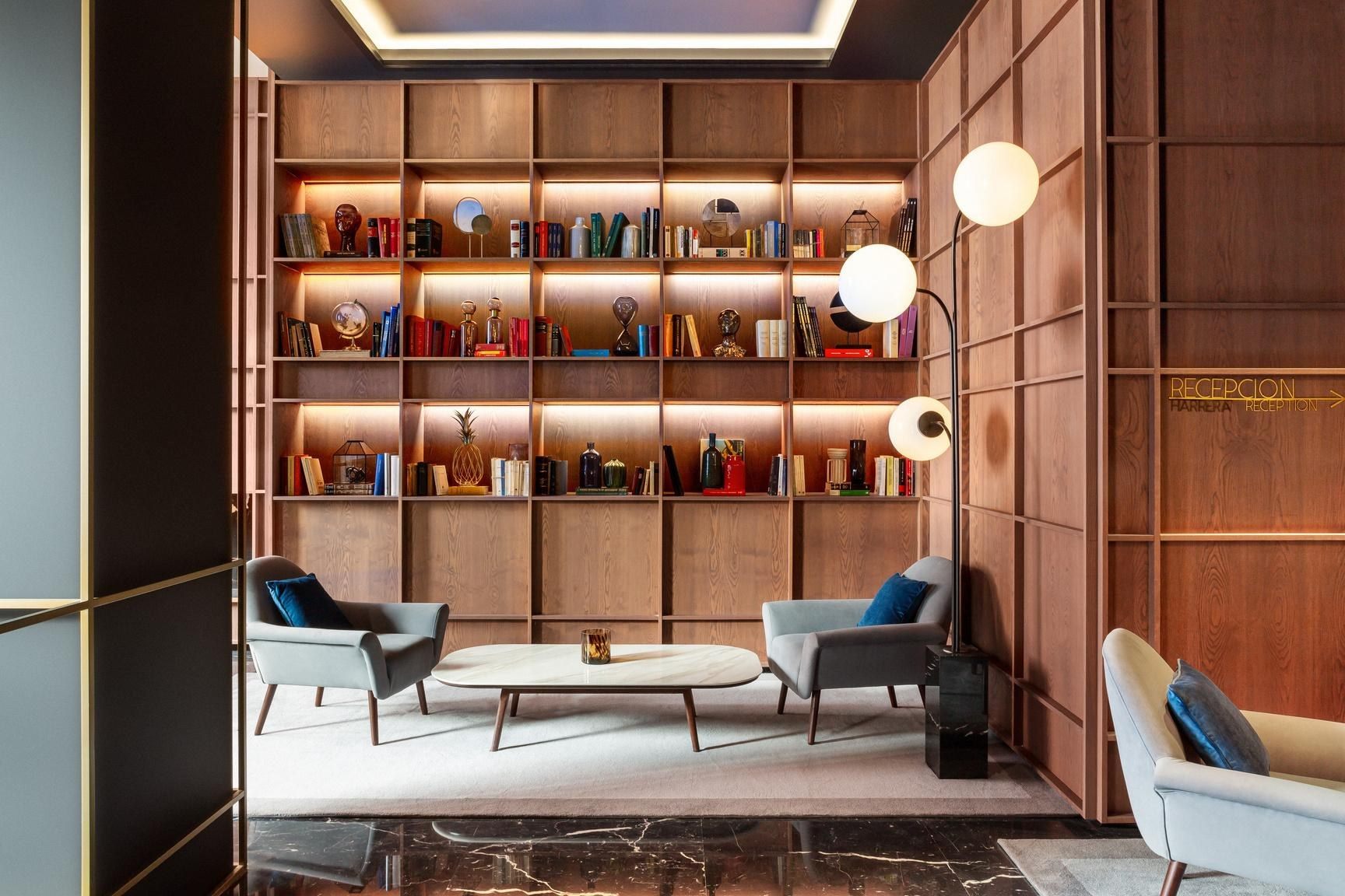 Biblioteca con sillones y estantería iluminada